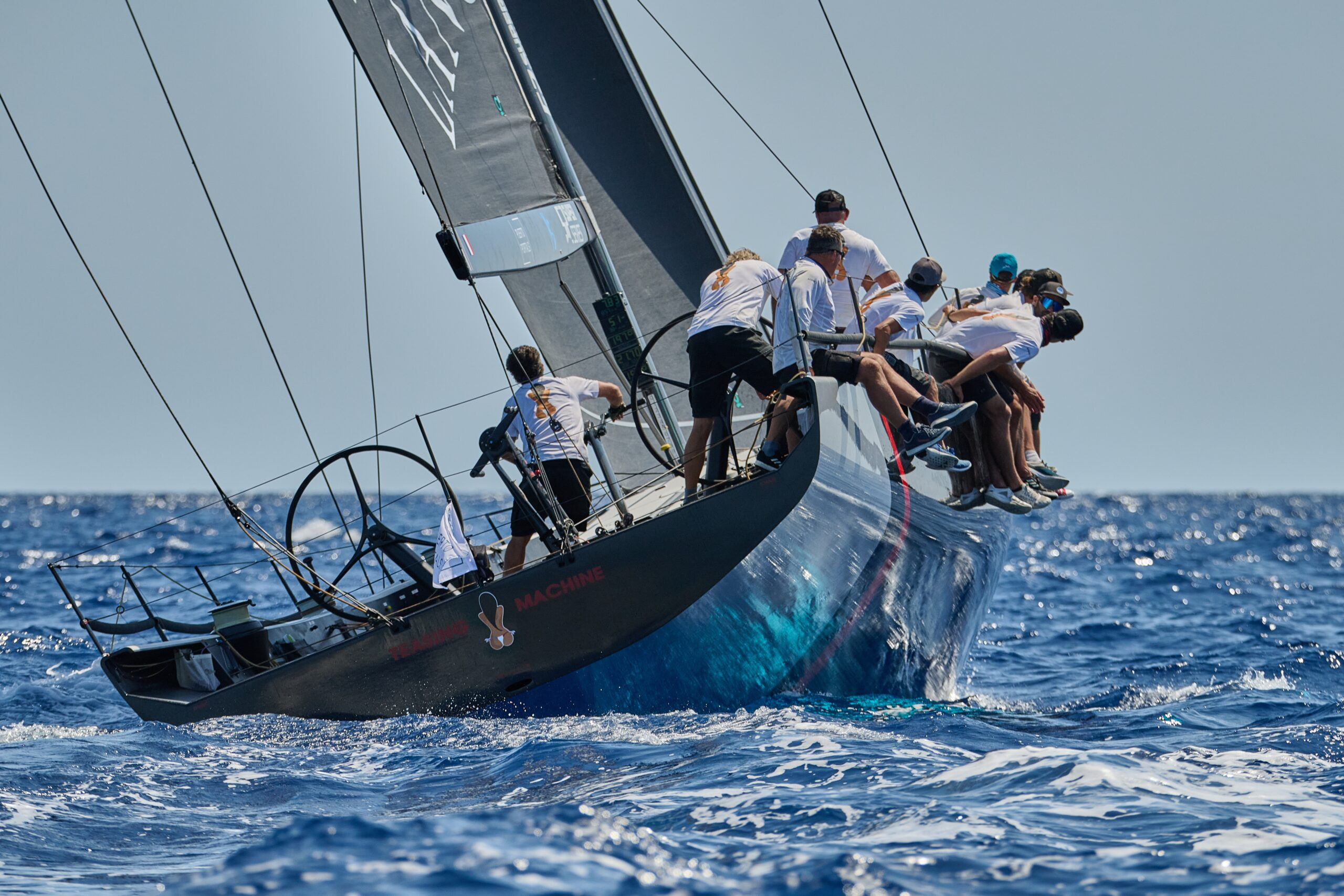 Sailing yacht tacking upwind with crew adjusting sails in changing wind conditions