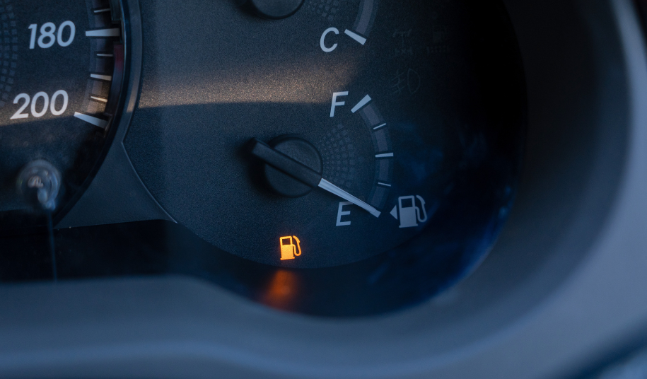 Car dashboard fuel gauge showing an empty tank with the fuel warning light illuminated, symbolising this week's 5.6% surge in Brent crude to $76.18 a barrel