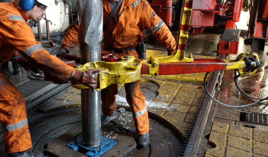 Oil workers operating drilling equipment on an offshore oil rig